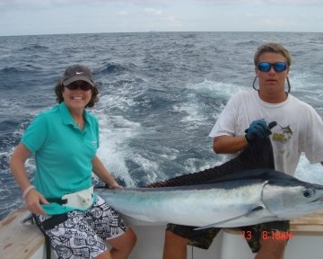 Man and woman holding a white marlin on boat